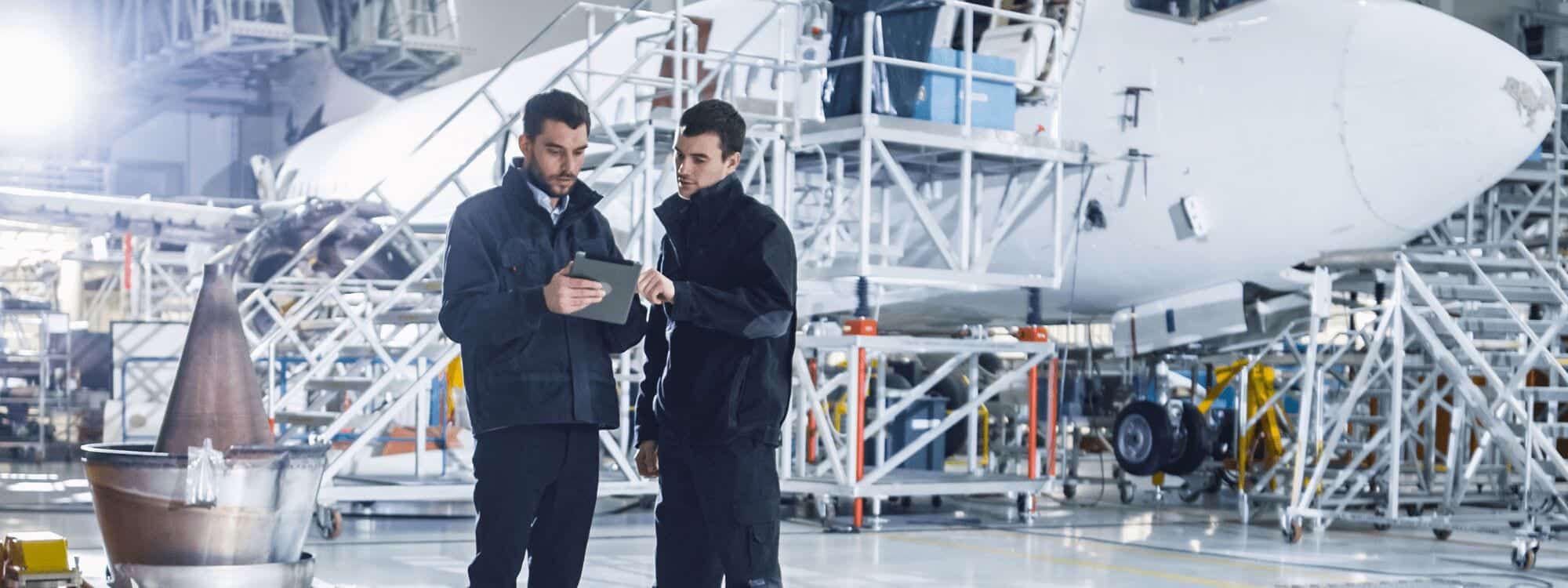 Two maintenance workers in an aerodrome hangar discuss how to implement recently learnt safety improvements from a Southpac Aviation Maintenance Human Factors Course.
